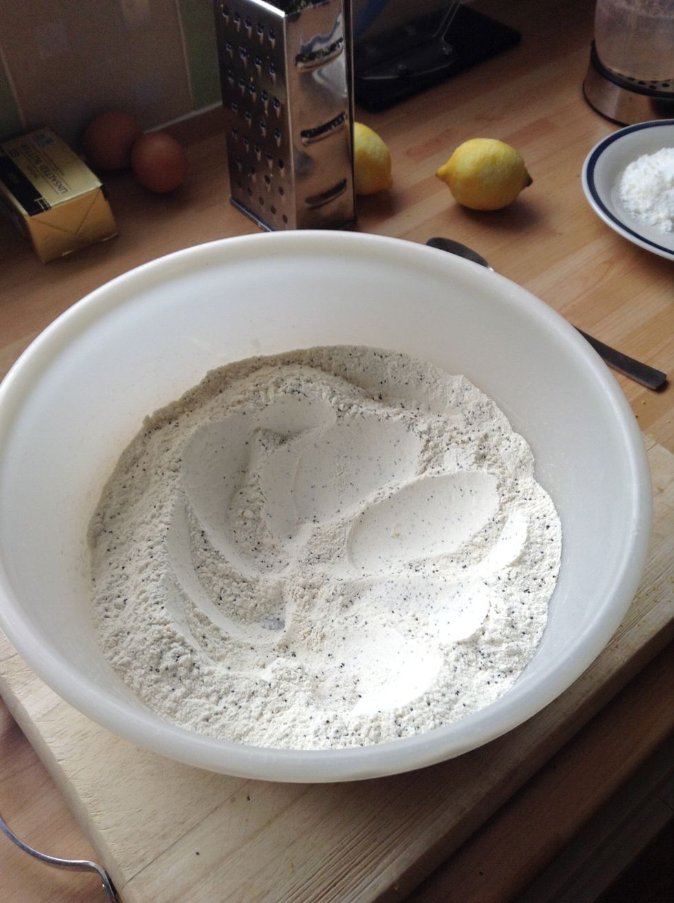 Add in the flour and poppy seeds to the lemon and sugar mix. Then combine the mixture and make a well in the centre