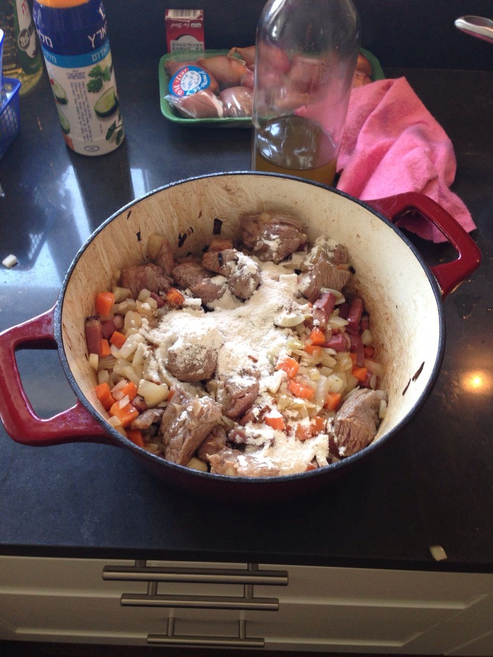 Add in the meat and bacon in to the casserole. Add flour, salt and pepper and mix.