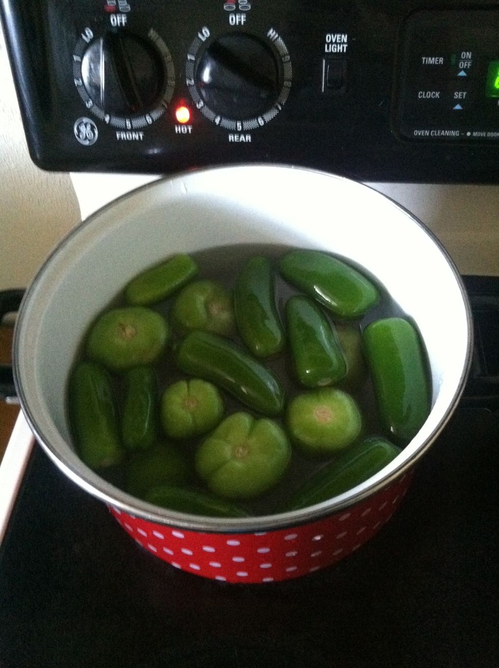 Add jalape\u00f1os and tomatillo in the sauce pan with water. Put on stove over medium heat.