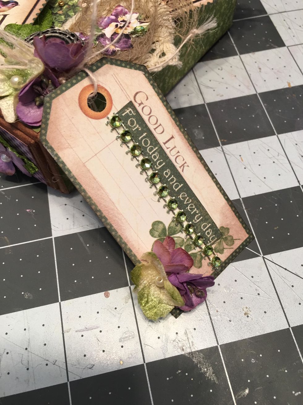 Add more decorations to the tag on the outside of the box by gluing a strip of green rhinestones and a strip of paper that says "For today and every day" as shown.