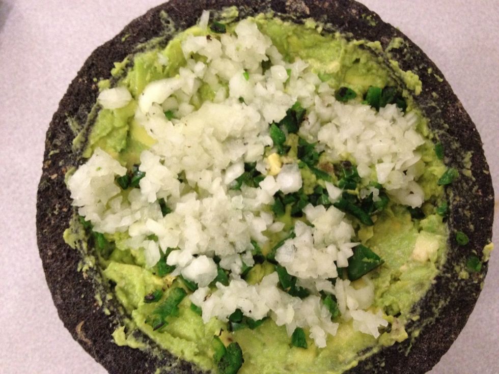 Add more diced onion, jalape\u00f1o, and cilantro leaves to the molcajete. Use the stone or a fork to mix into the avocado paste.