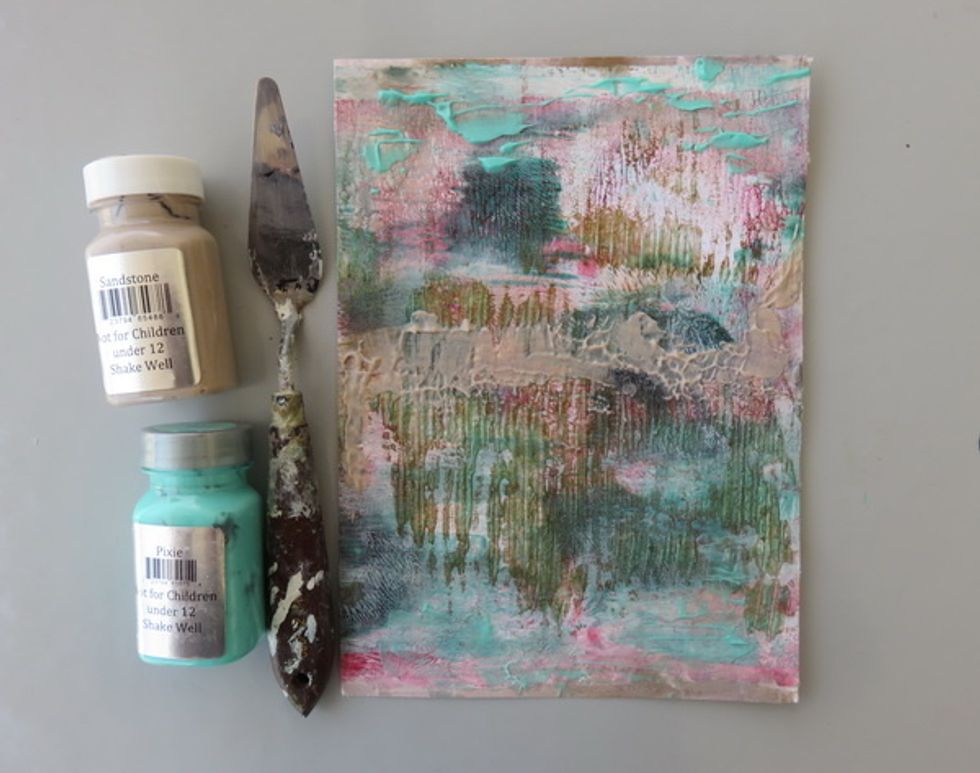 Add more of Pixie paint to make the sky like texture. Add Portobello paint in the middle to look like mountains. Dry with your heat gun to get the bubbles and the texture.
