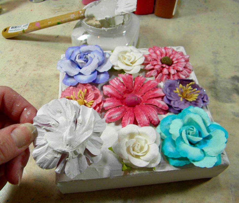 Add Mud to the back of the flowers and place them down onto the canvas.  When dry, the Mud acts as glue and holds the flowers in place.