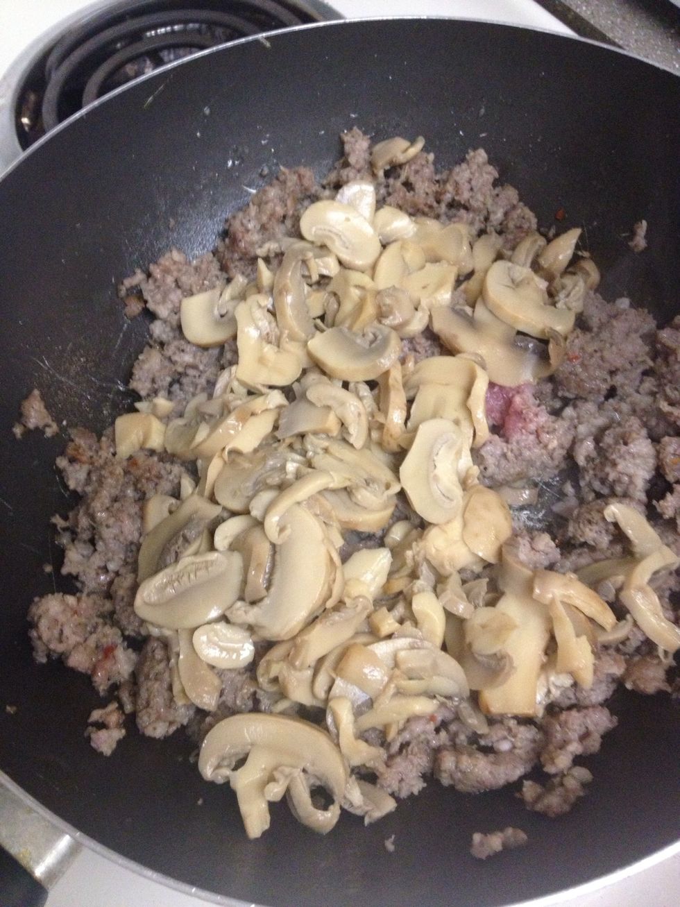 Add mushroom to the frying sausage.