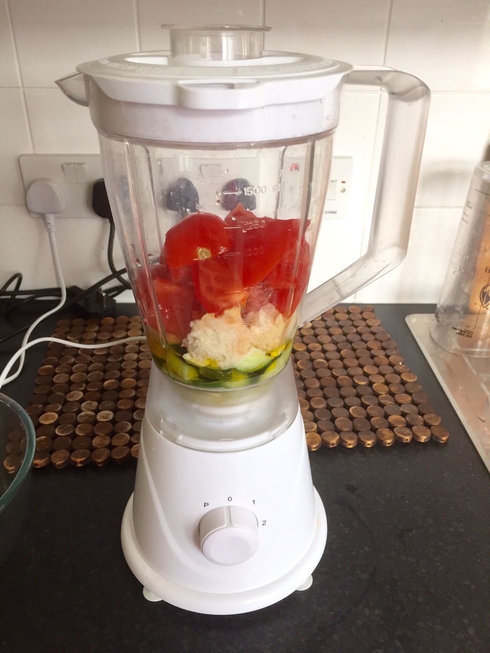 Add oil, pepper, cucumber, garlic, a bit of bread, a bit of the tomatoes and some water to a blender. I love garlic, so I used 4 cloves this time.