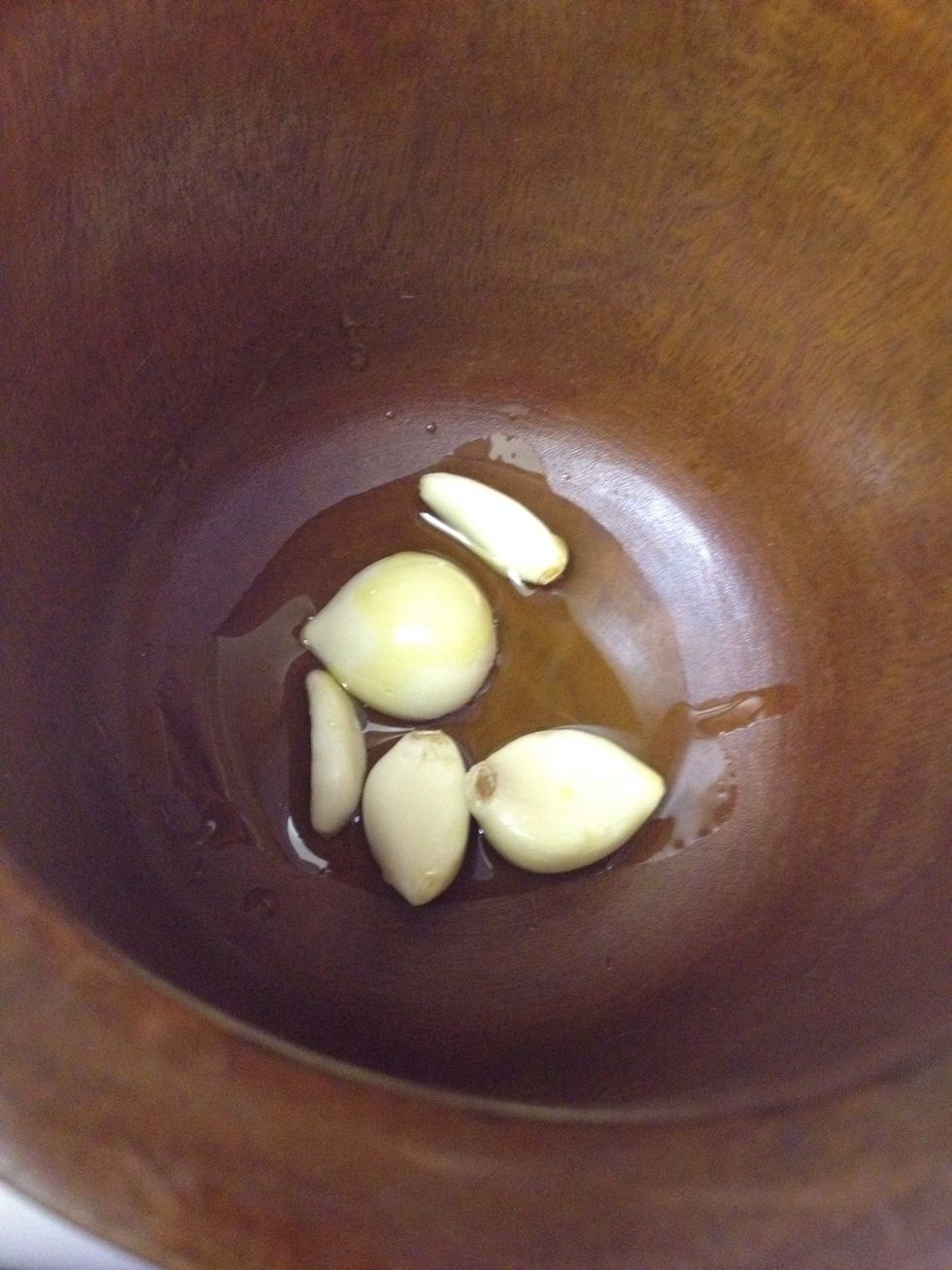Add olive oil, salt and a few garlic cloves to a mortar & pestle.
