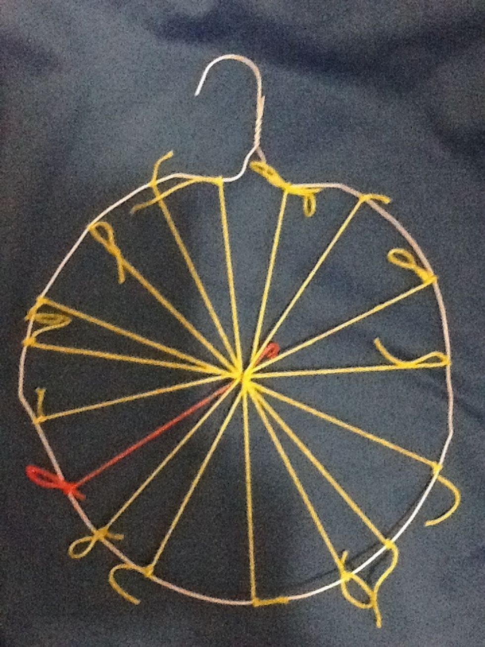 Add one piece of string and tie together the middle strings and tie the other end to the hanger (radius). It's a different color here just to show you where it is. You need this odd number to weave.