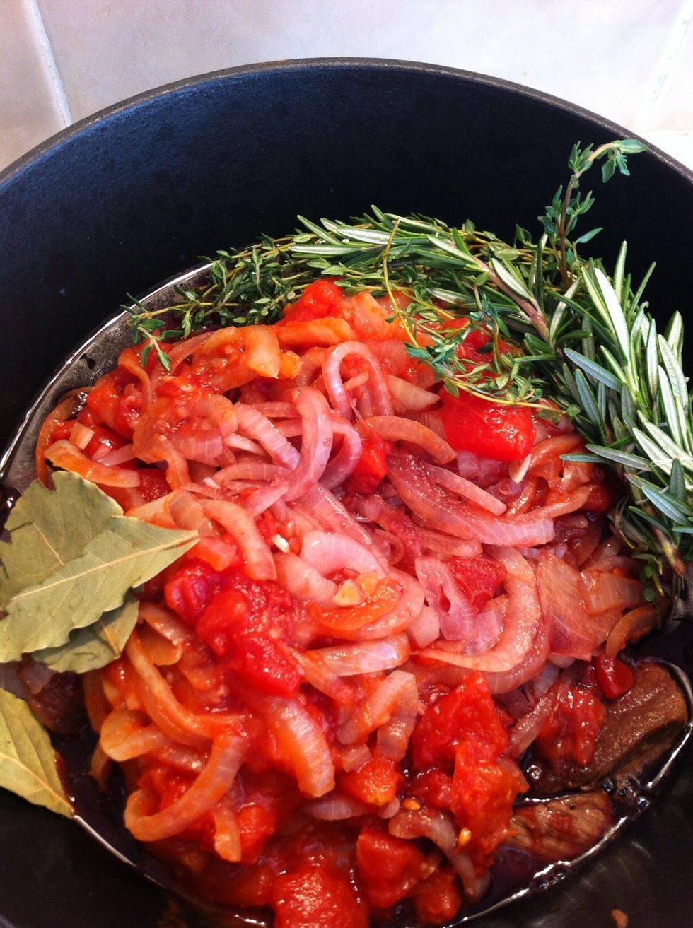 Add onion back to the pot with the beef, add red wine, diced tomatoes, herbs, and make sure the liquid just covers the meat, otherwise add more water or beef stock, season with salt and pepper.