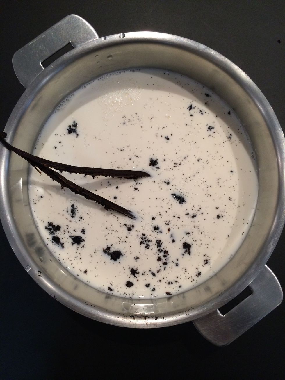 Add over the milk. Also, You could add the bean in the milk or put it in the sugar so u will have vanilla sugar. Let simmer on low