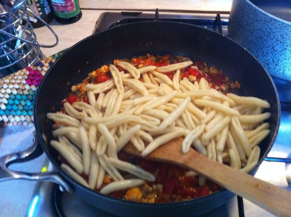 Add pasta to the fish sauce along with sliced green olives and cook until the sauce thickens.