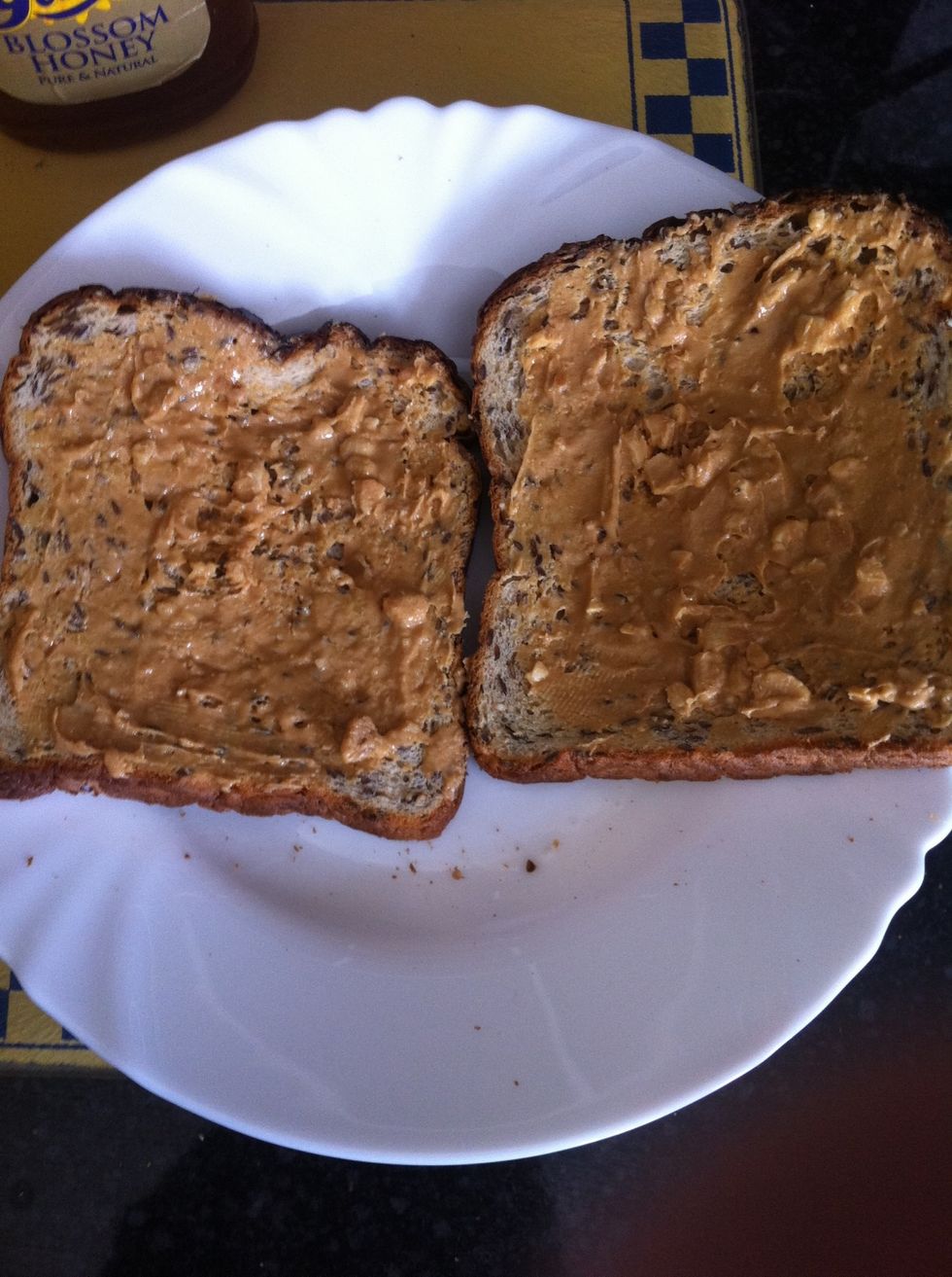 Add peanut butter to both toasts.