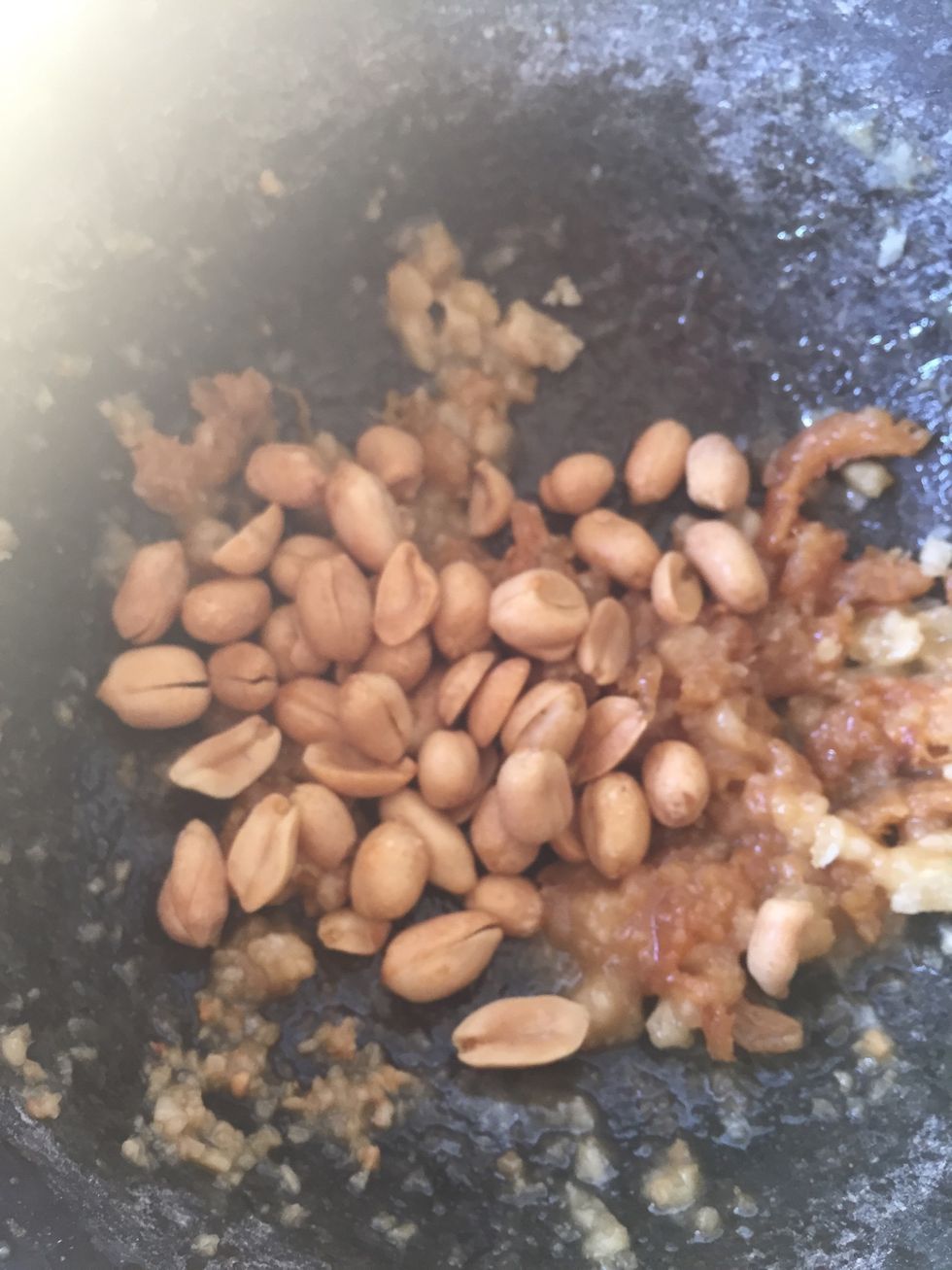 Add peanuts and salt, continue to pound until it's broken into small pieces.
