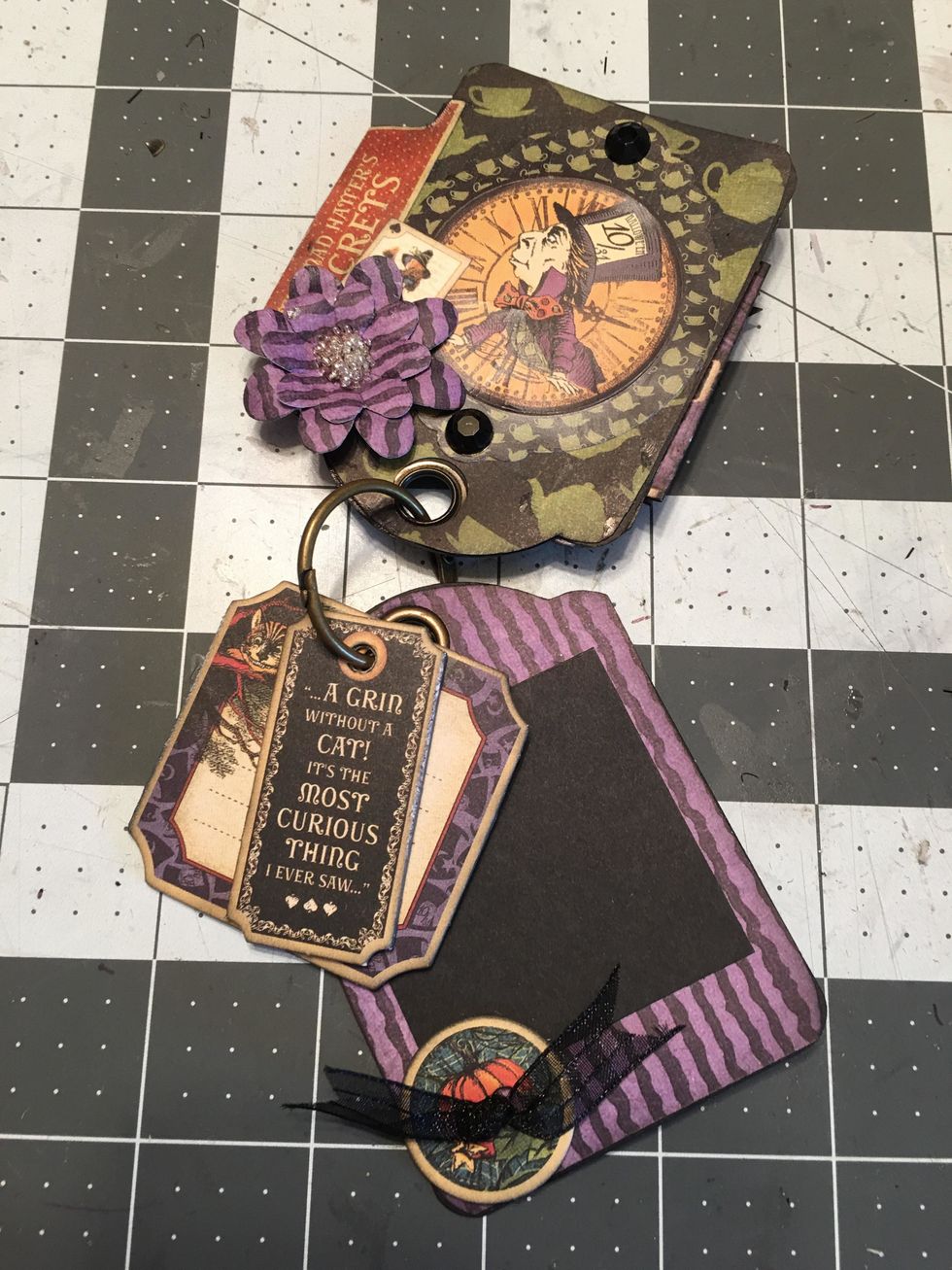 Add photo mats, chipboard buttons, ribbon and add chipboard tags on to the ring of the album as shown in this photo.