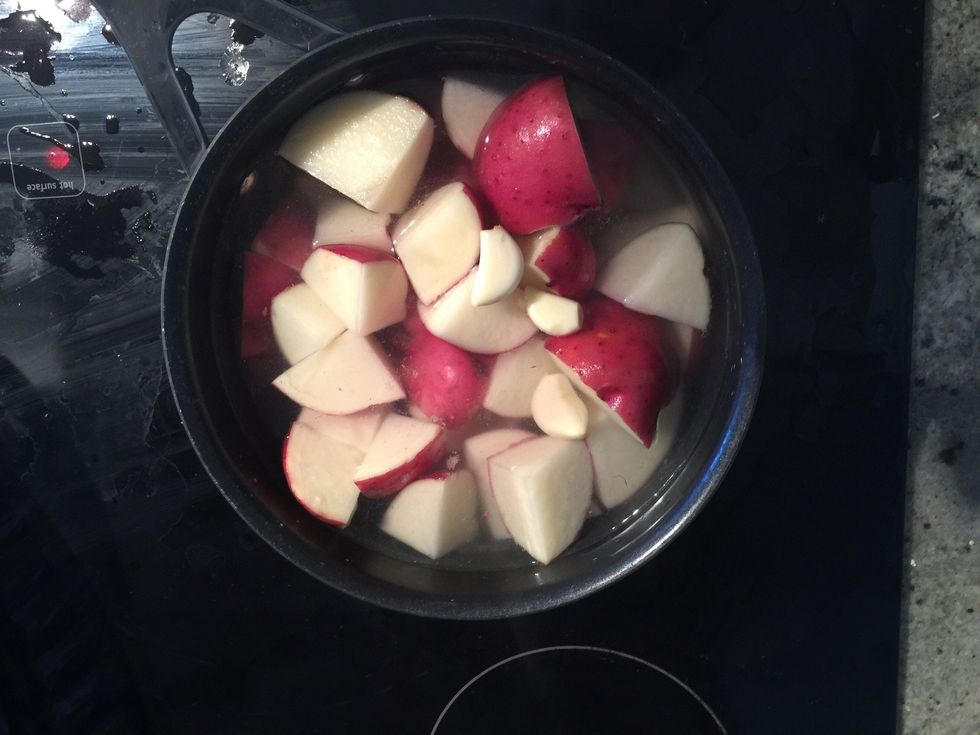 Add potatoes and garlic cloves into boiling water