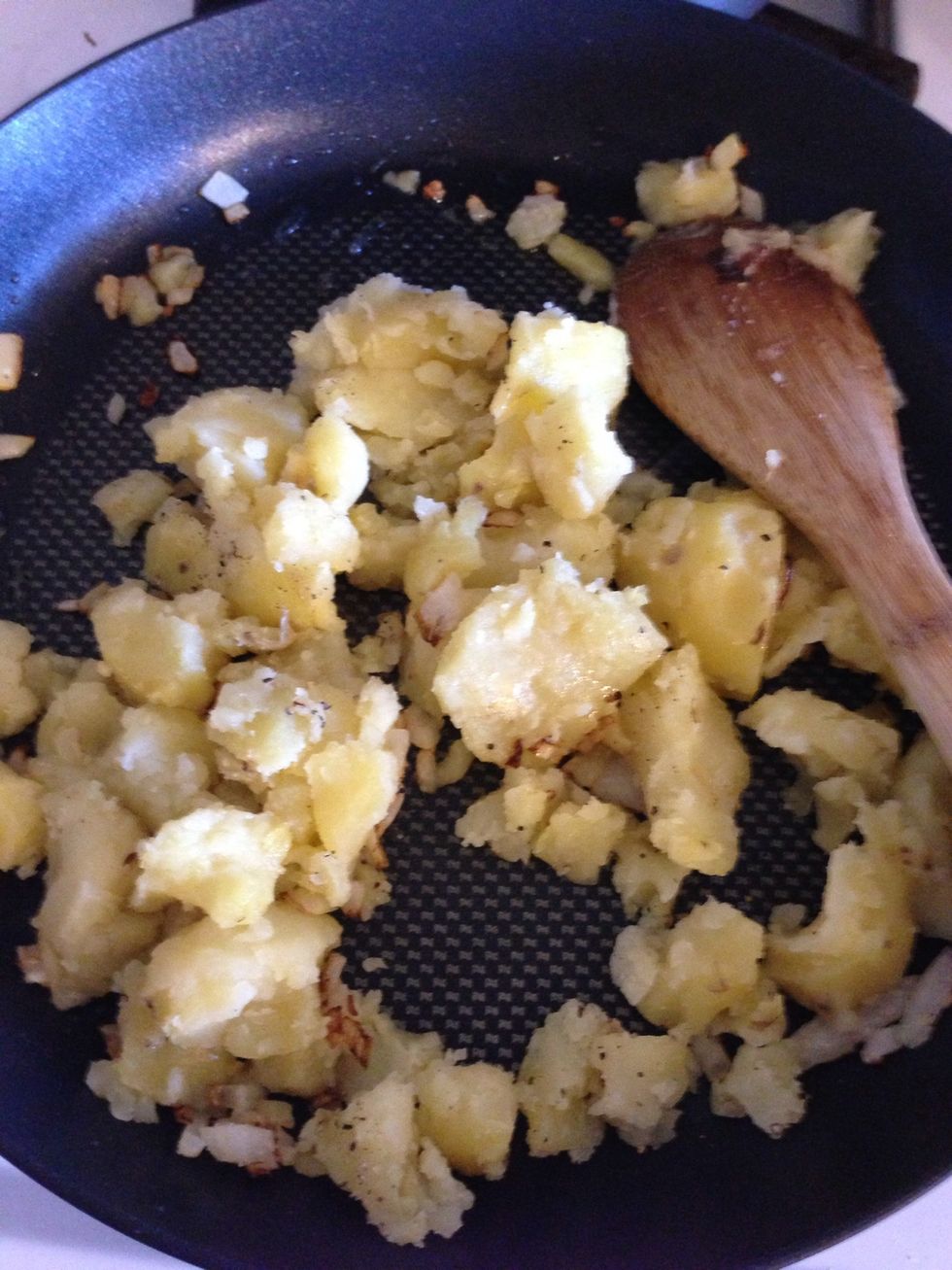 Add potatoes in and mash them. Add salt and pepper. Five minutes is all they need in the pan. Don't worry if you don't mash the potatoes all the way. That's the next step.