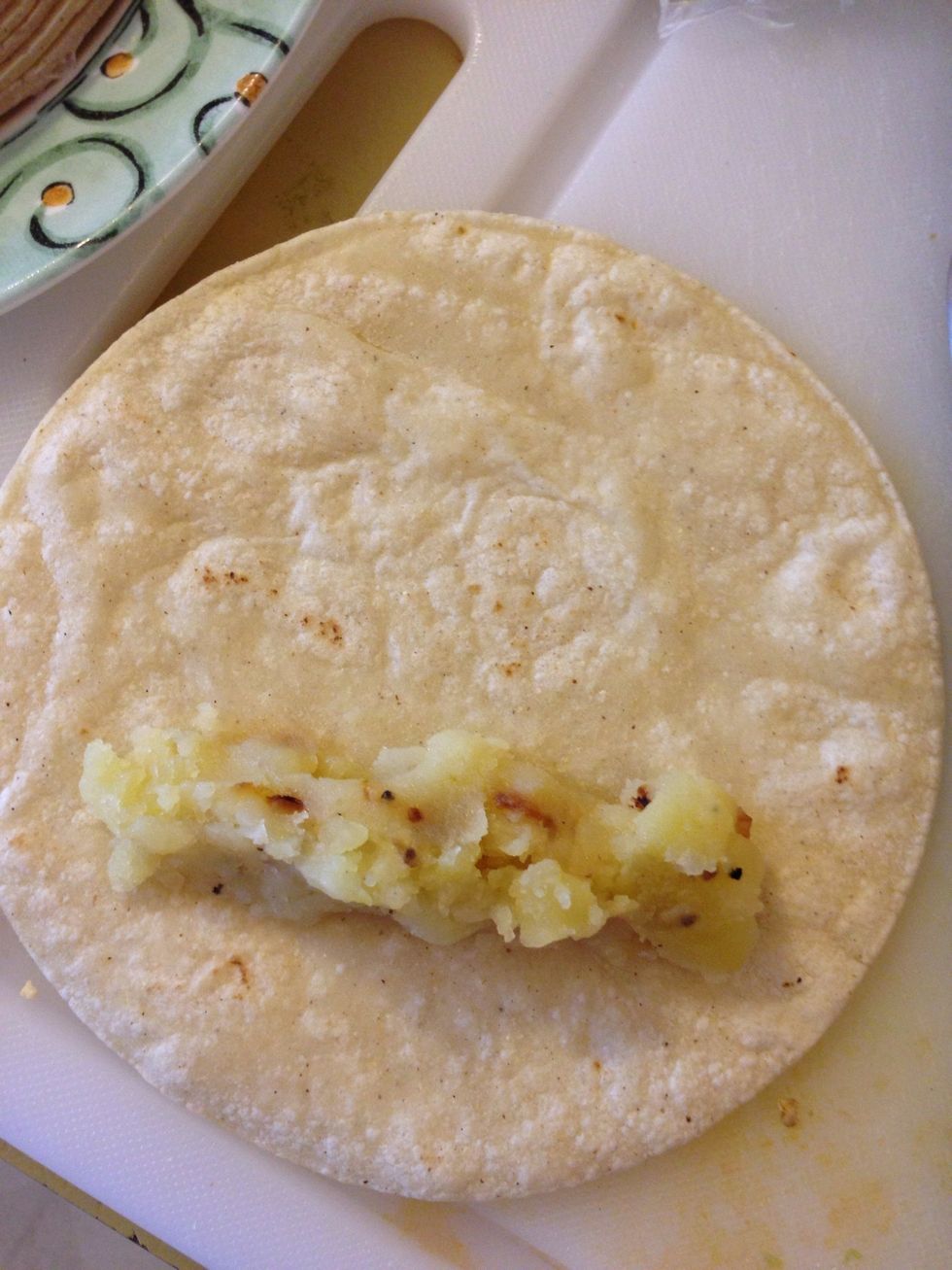 Add potatoes to the tortilla. Roll it up. Don't add too much chicken or potato because if it comes out when frying it makes the oil pop a lot and you don't want hot oil on your skin!