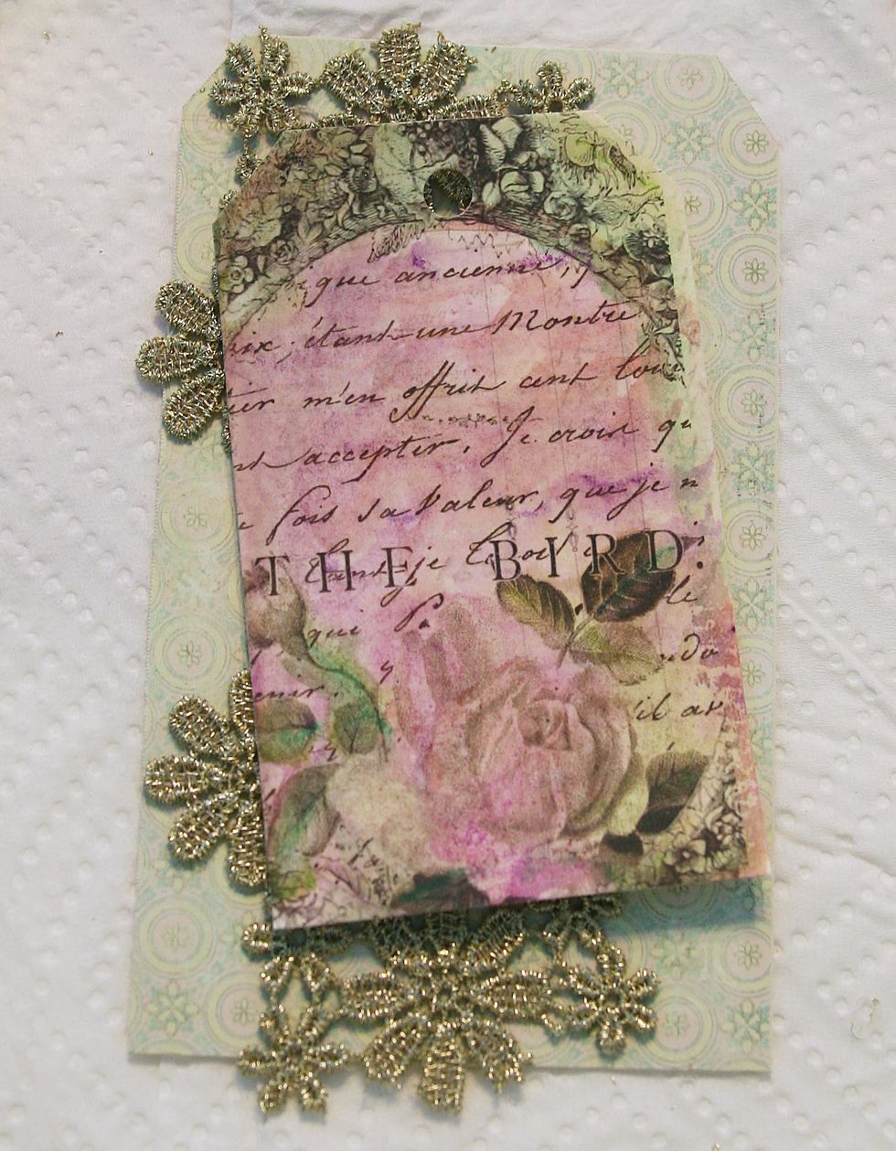 Add Royal Menagerie paper to a 3"x5.5" manilla tag. Adhere gold trim as shown. Adhere Paintable tag with foam squares.