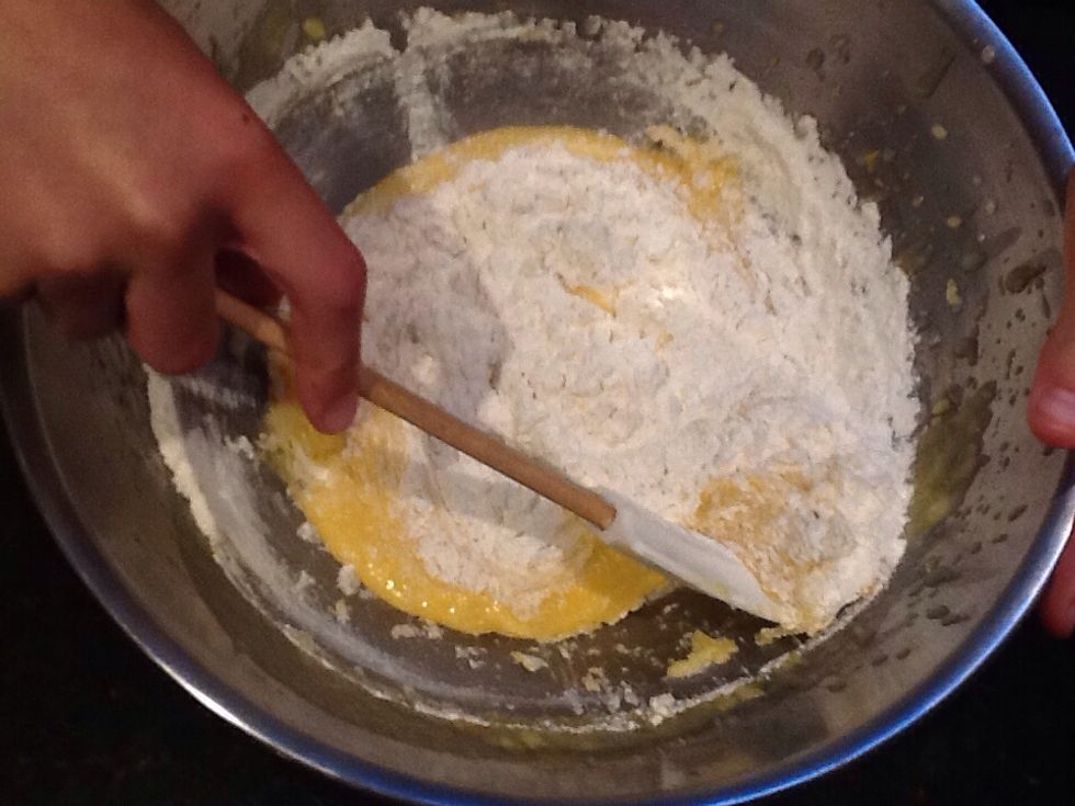 Add sifted flour into the bowl and start mixing with a spoon