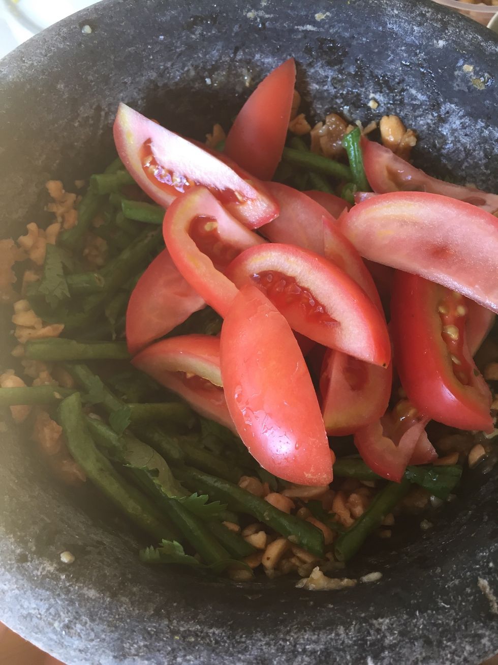 Add sliced tomatoes and pound it. You want to pound until the tomatoes juice to come out.