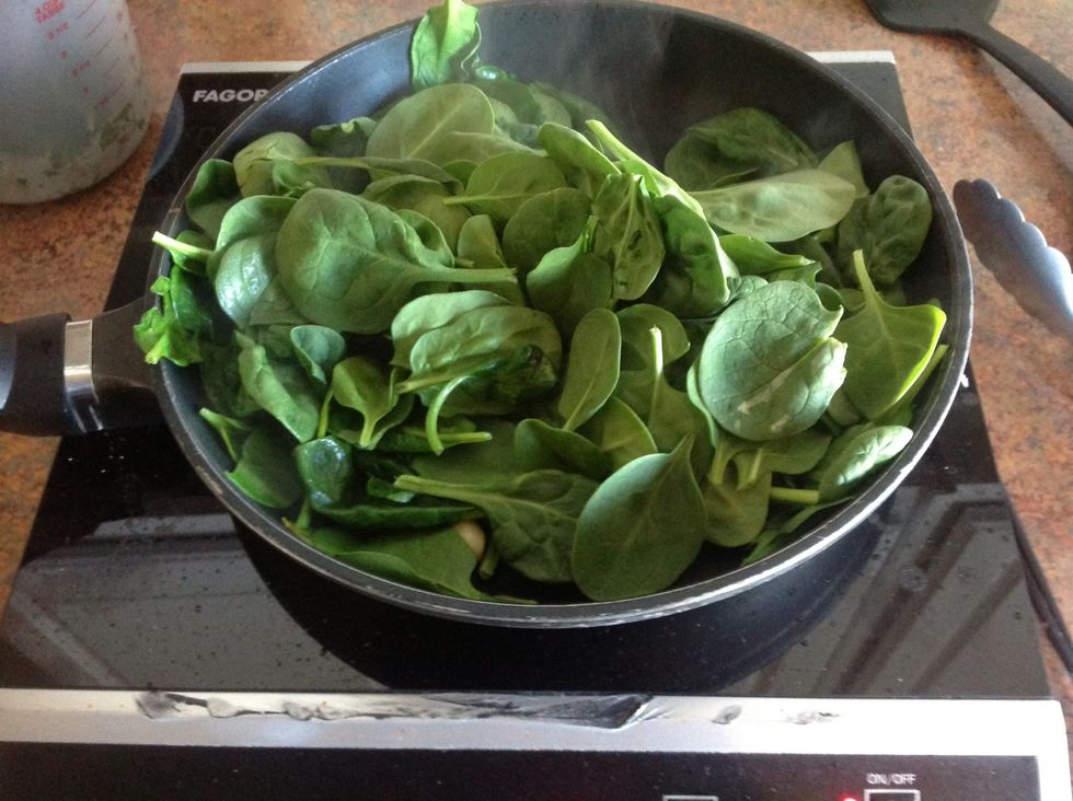 Add small amount of olive oil to skillet. Saut\u00e9 2 garlic cloves until softThen add spinach and cook until wilted.