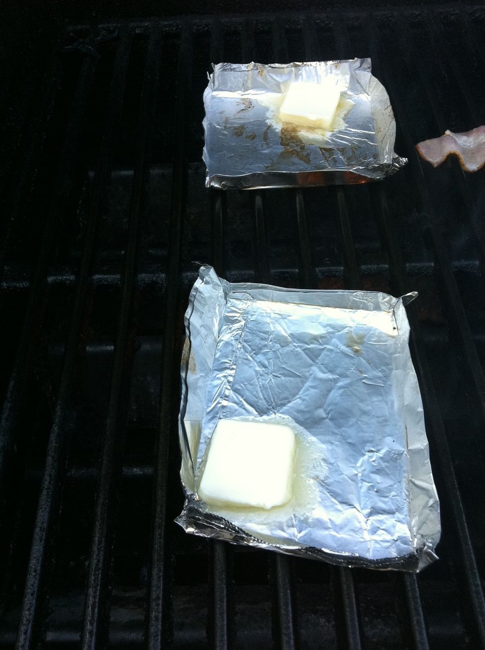 Add small slice of butter to each foil tray and melt.