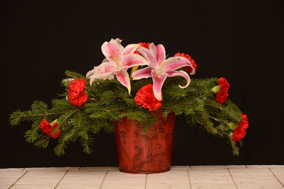 Add some carnations around the extremities of the arrangement. A few are also placed around the other side facing away from the camera.