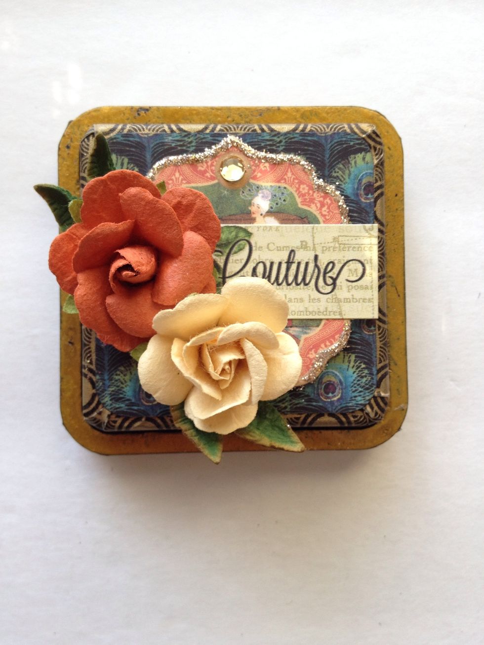 Add some extra leaves underneath the flowers. I used some Petaloo Foliage for this. Then adhere the word "couture" from your sticker sheet.