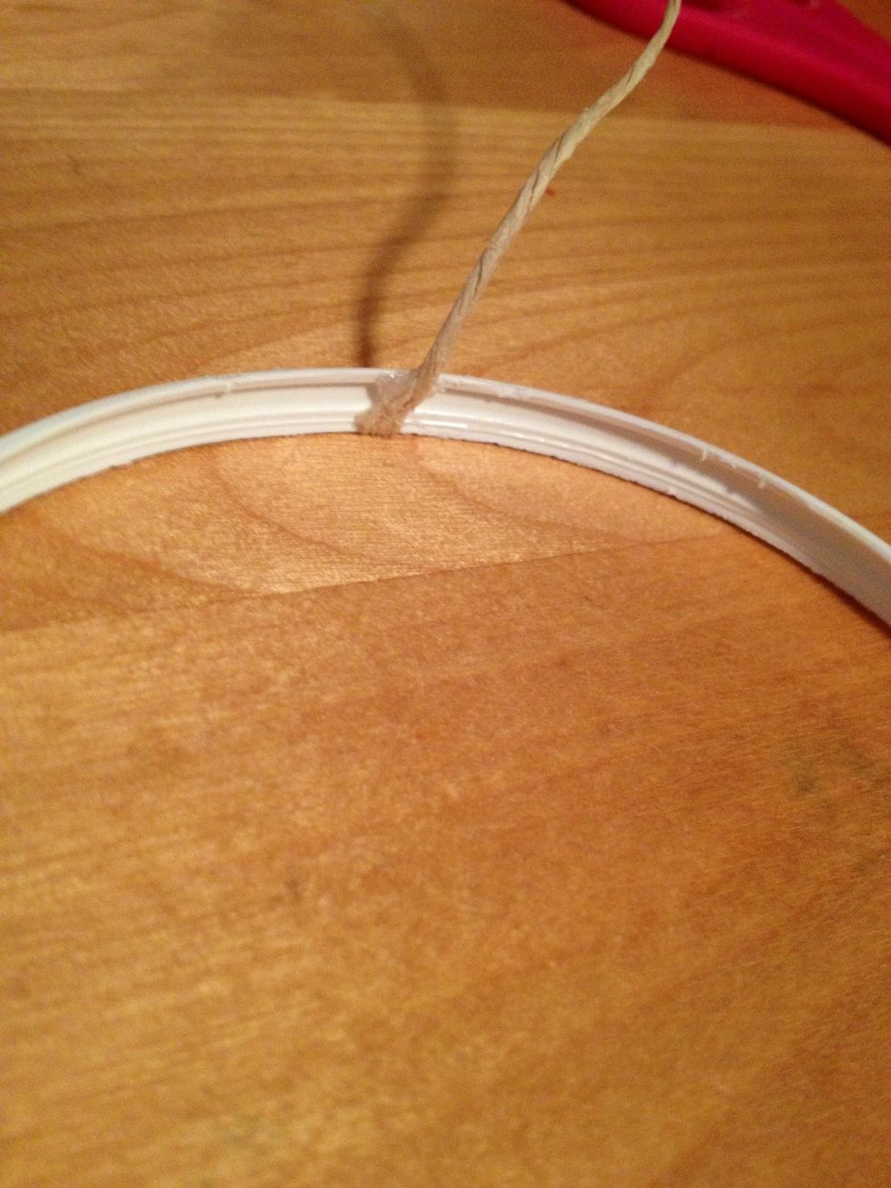 Add some hot glue inside the ring and attach the string.
