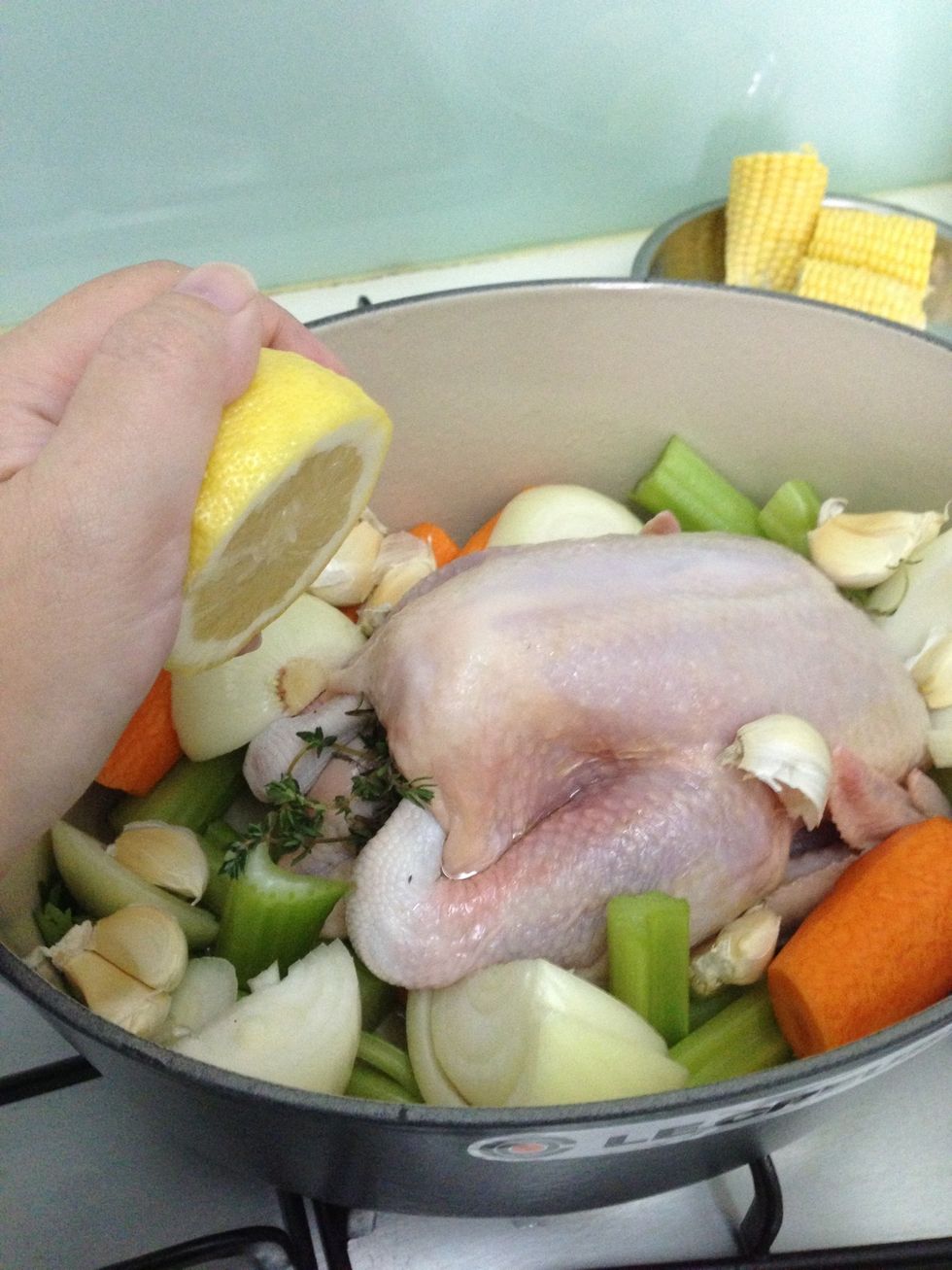 Add some lemon juice all over. Then stuff the lemon into the chicken cavity. Put the entire casserole into the oven. Lower the temperature to 200c.