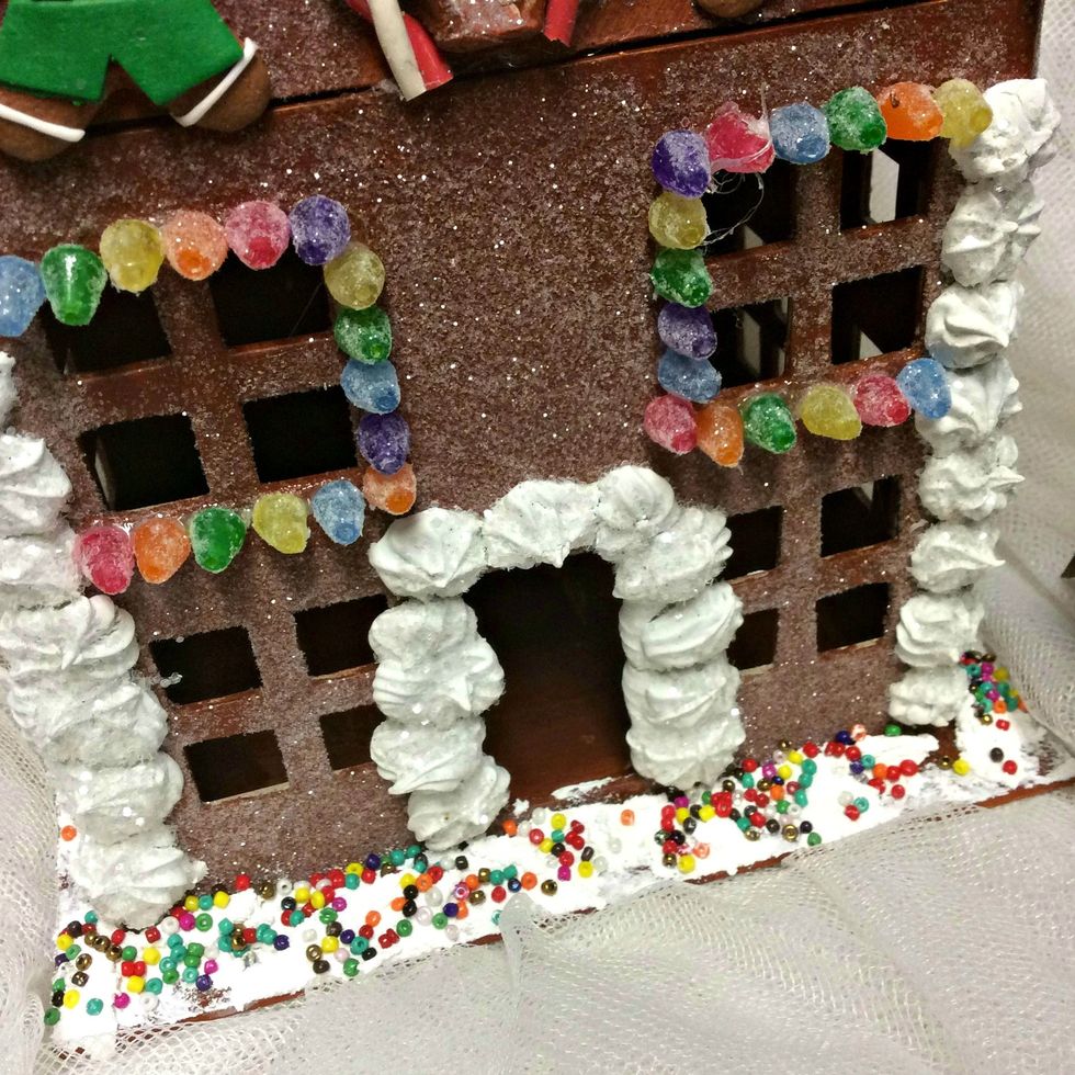 Add some modeling paste to the base of the house and sprinkle seed beads. They look like sprinkles. The candy around the windows are ornaments for miniature Christmas trees. I sed E6000 glue for this