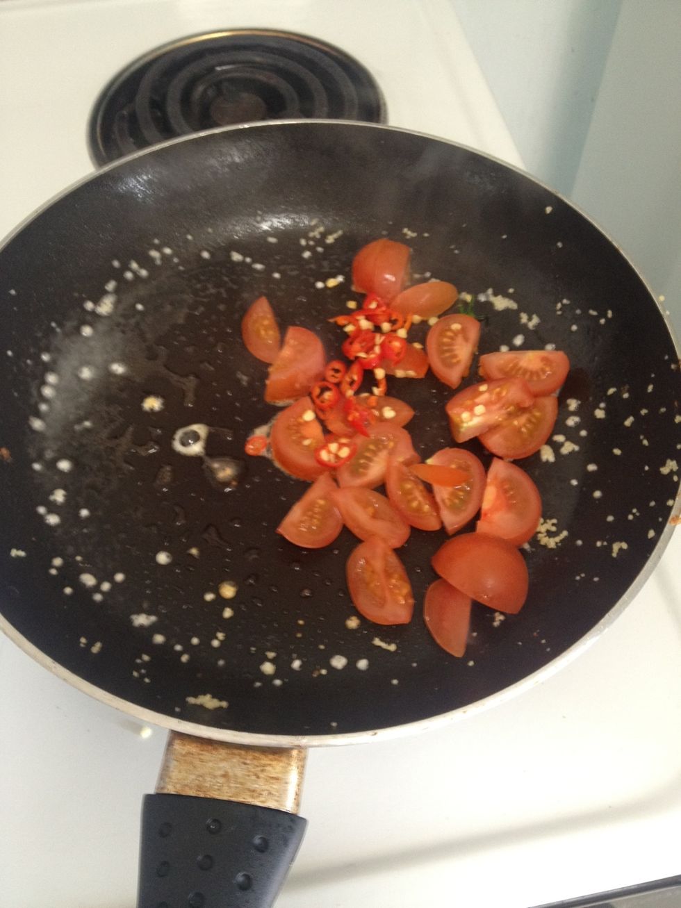 Add some oil spray to the pan, and fry the chilli and tomatoes together, fry for 30 seconds. BEWARE When frying chilli with its seeds as it can create a harsh oder that can cause you to cough.