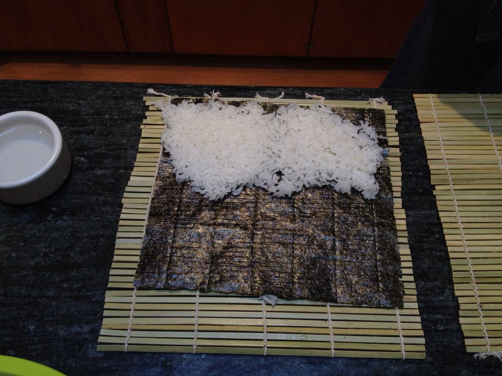Add some sushi rice to the nori roll. Not too much and make sure to pay it down a bit using a rice spatula.