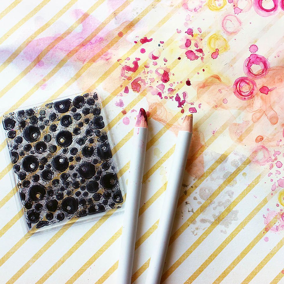 Add splashes of color with a stamp. Wet the stamp a little using a sprayer, then rub the pencil on top. Stamp to your background and dry.