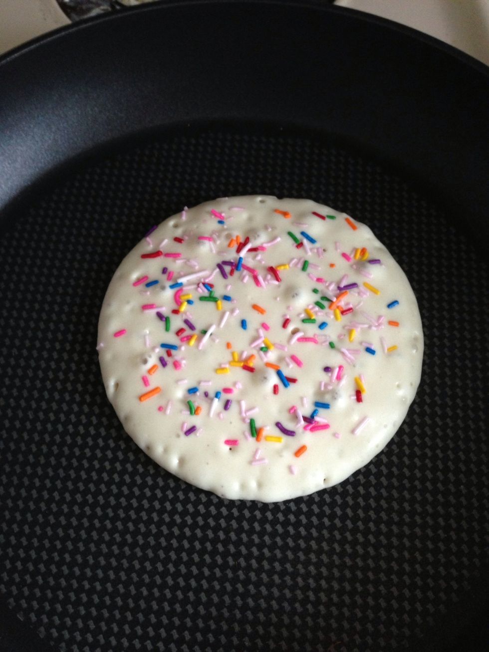 Add sprinkles to the uncooked side of the pancake.