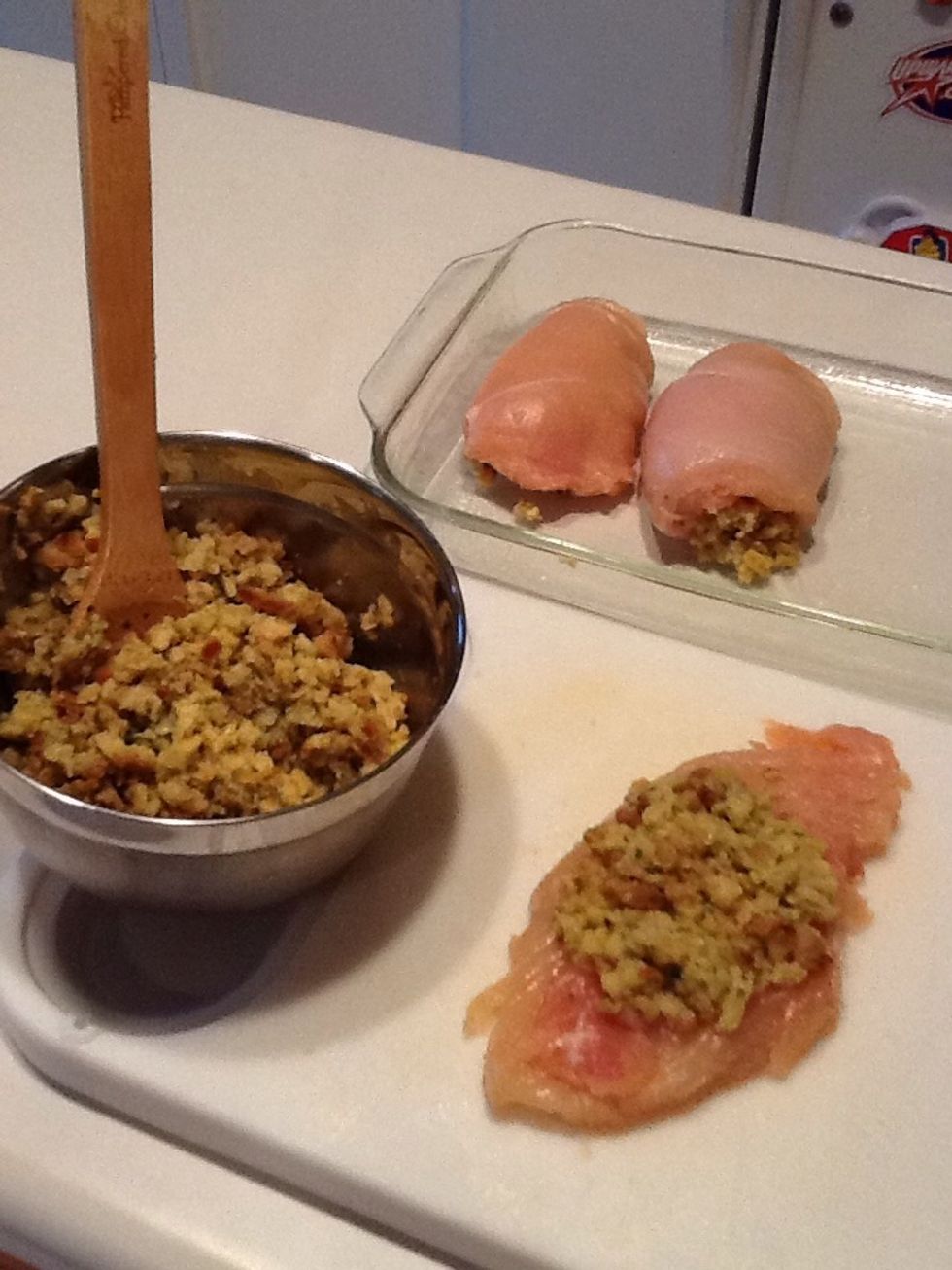 Add stuffing to chicken breasts. Fold edges together and place in the baking pan, seam side down.