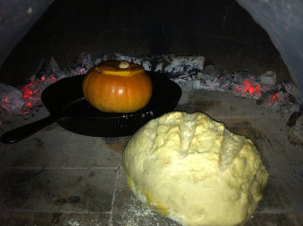 Add stuffing to pumpkin & place pumpkin in cast iron skillet. You can either push coals to the sides of cob oven or remove them before cooking. Put pumpkin & other baked items (like bread) in oven.
