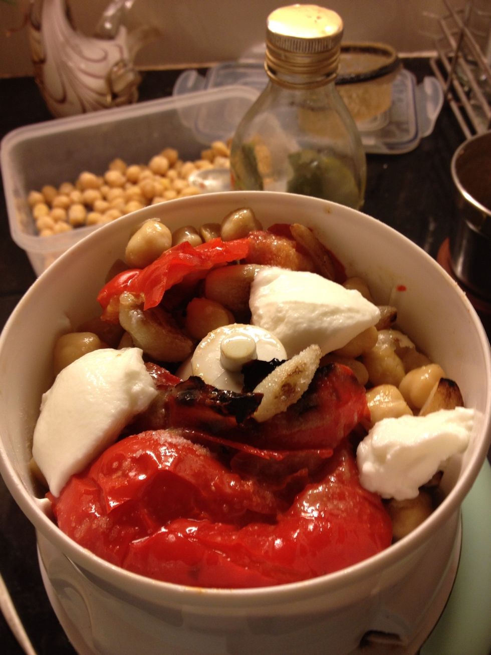 Add tahini paste, garlic, roasted red bell pepper, yogurt, salt, olive oil and some water. Now grind away.