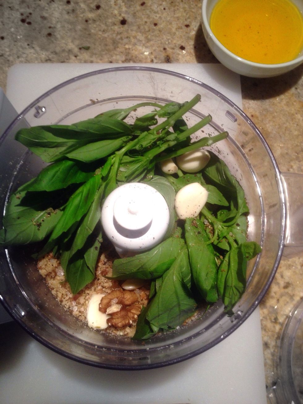 Add the basil, garlic, salt and pepper in with the walnuts and pulse. Then slowly add 1/2 cup of olive oil whilst the food processor is still running, until it has created a rough pesto. Taste :)