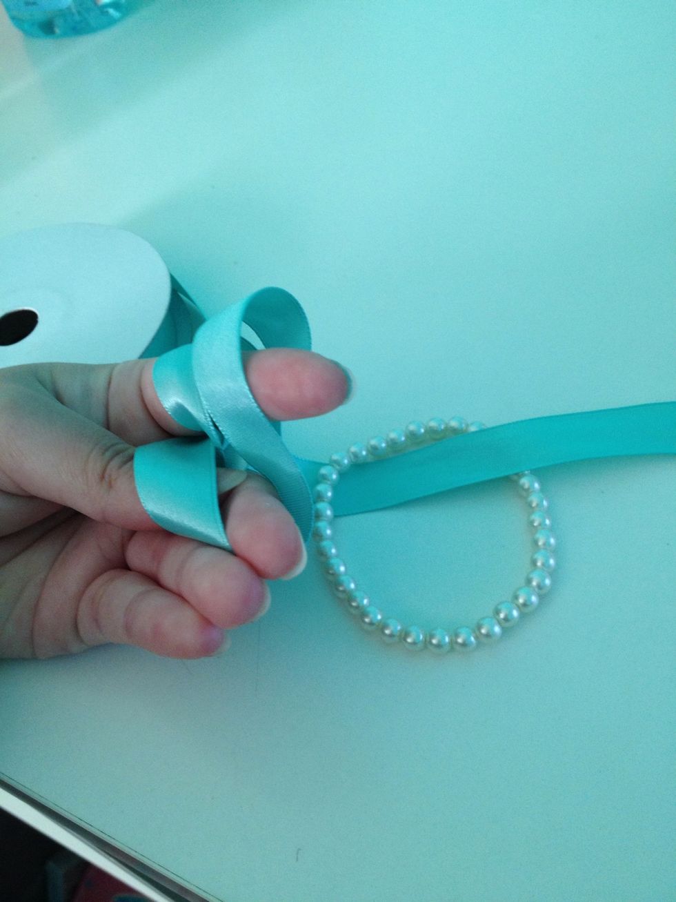 Add the bracelet through just like that. Push it further up (it'll just be easier to tie). Weave the strand through the loop (like before).