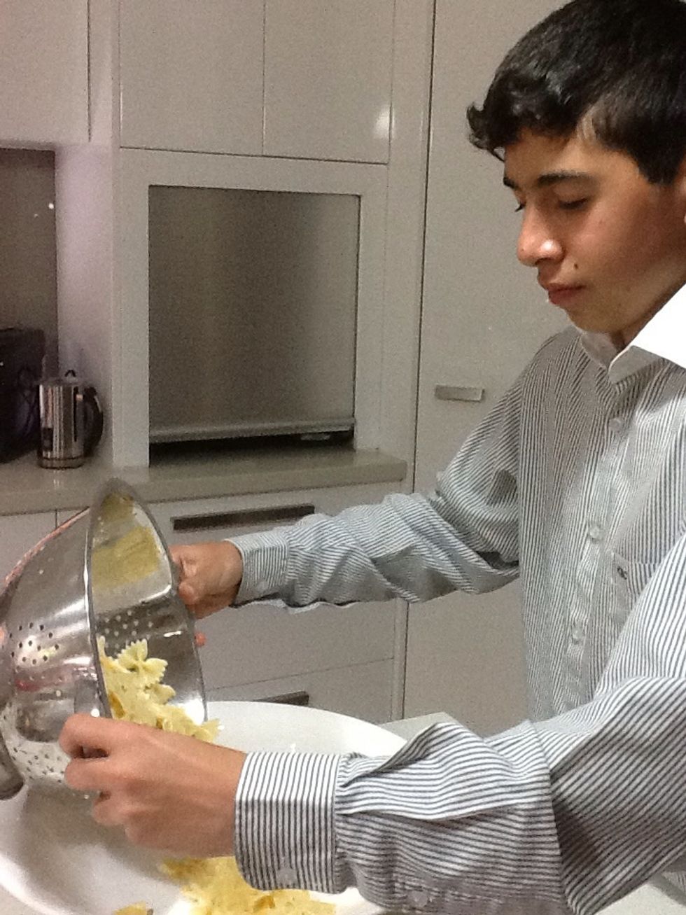 Add the dry pasta, tomatoes, cucumber, onion, prawns, olives, watercress and salad dressing to a large serving bowl.