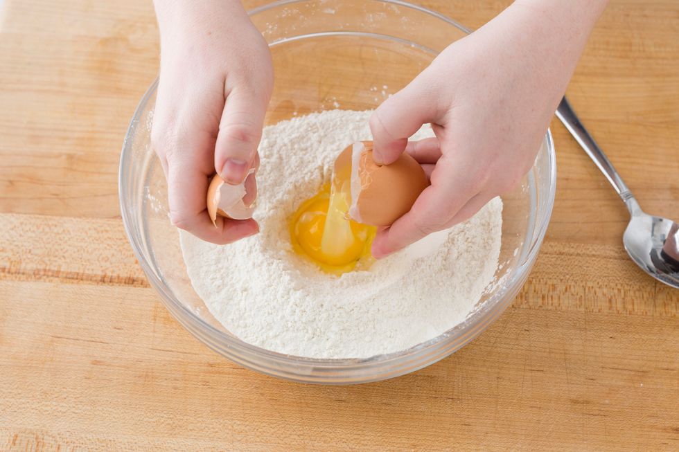 Add the egg into the center of the well.