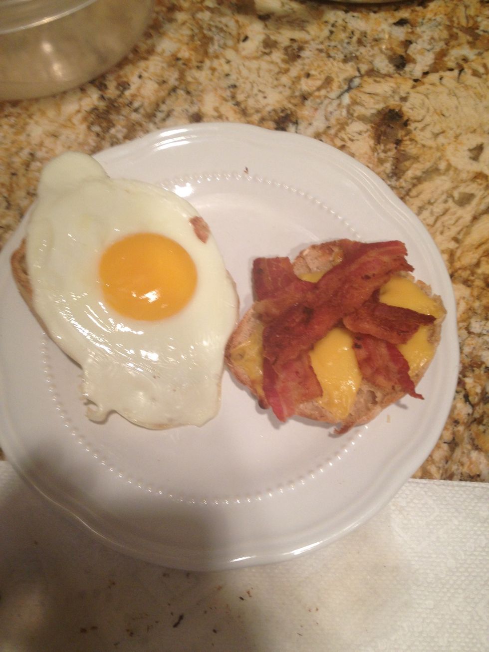 Add The egg to one English muffin side and bacon to the other
