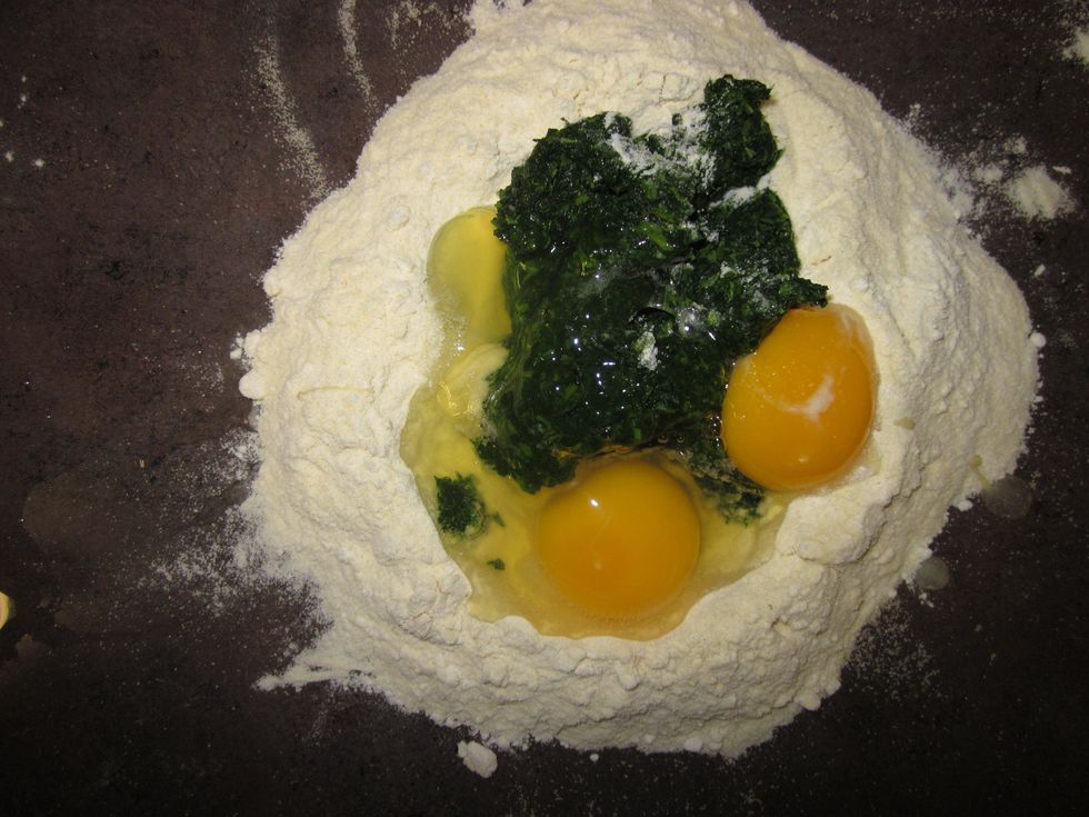 Add the eggs, oil, salt, and spinach to the middle of the well