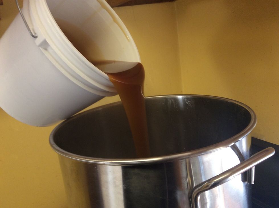 Add the extract to the wort. We turned off the heat so the extract doesn't burn as it hits the bottom of the kettle. I suggest warming up the bucket in hot water before this.