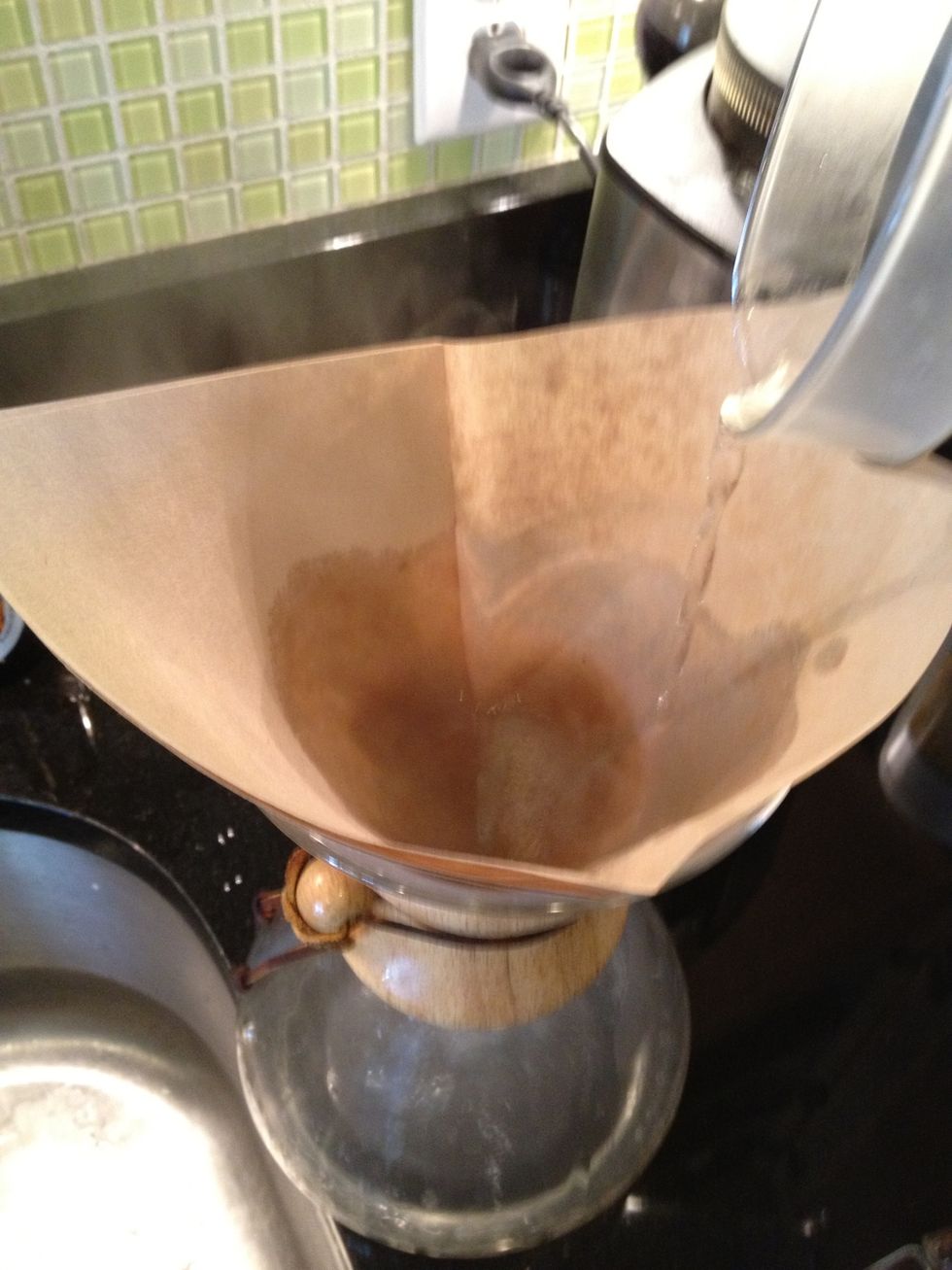 Add the filter to the Chemex with the three ply side in the spout. When the water is hot but before the boil, pour some into the filter to get rid of the paper taste, and heat up the pot.
