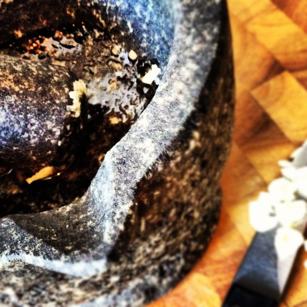 Add the garlic and 1 tablespoon of olive oil to a pestle and mortar and mix into a smooth paste.