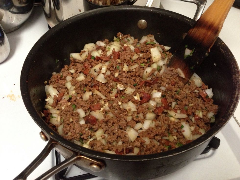 Add the ground beef and brown. Once browned add the chopped onions, garlic, culantro and seasonings.
