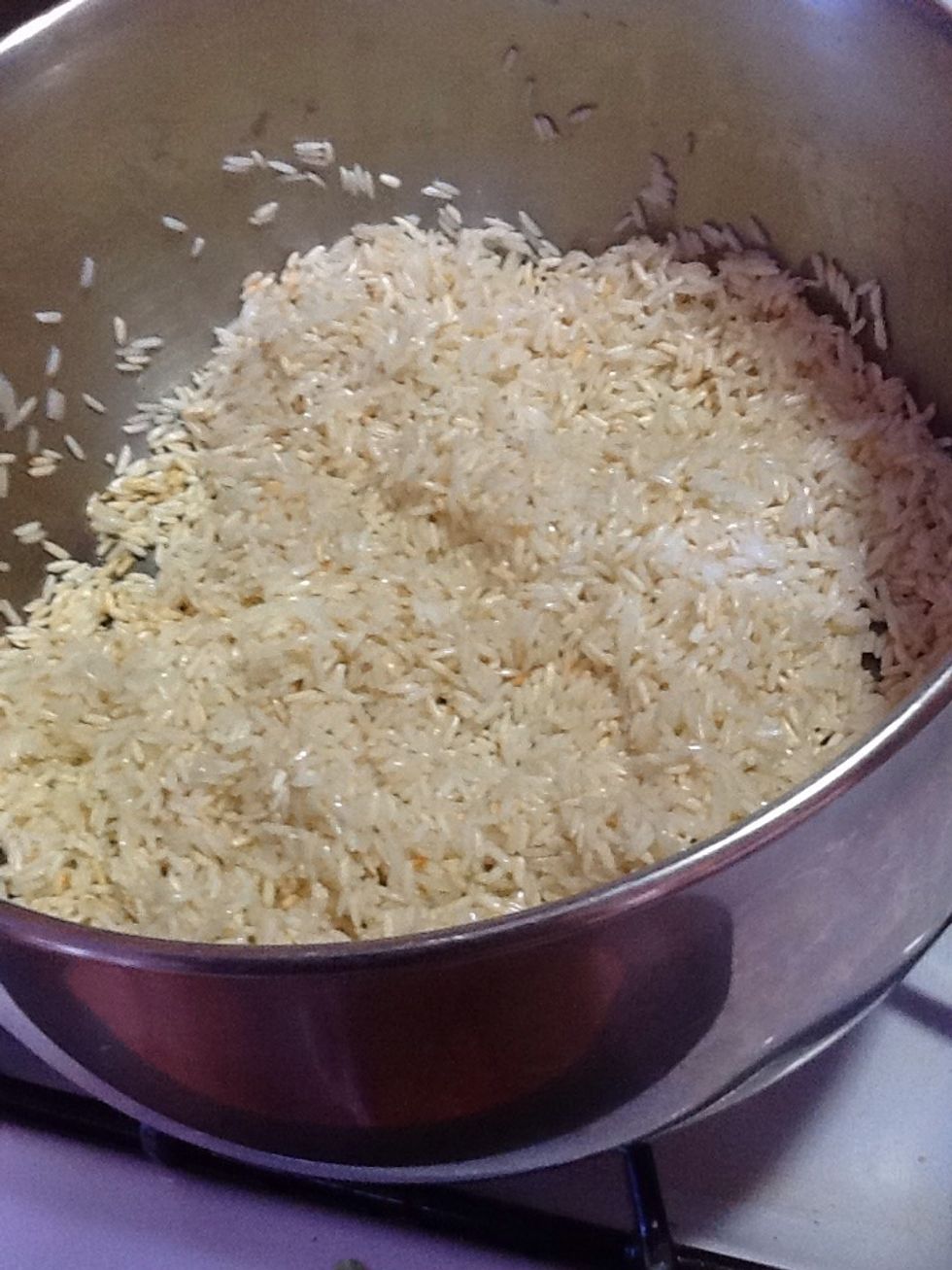 Add the olive oil and margarine to an pot once the mix of the two is hot add the row rice Fry on median heat but with a wood spoon mix it all in slow motion not let burn it soon is light brown