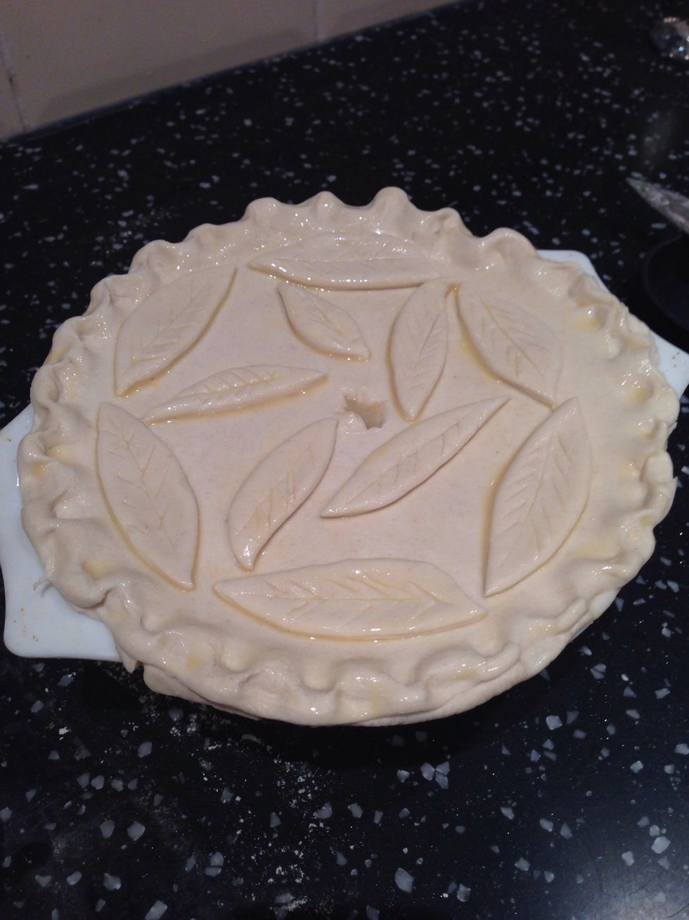 Add the pastry circle to the top of the pie dish and press/crimp the edges. Use any left over pastry to make leaf shapes and add these to the pie top. Use a small knife to make a hole in the centre