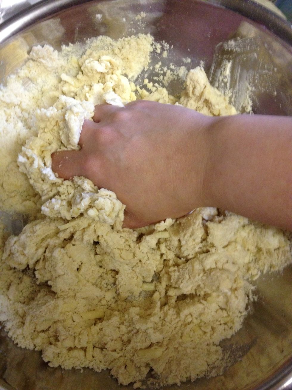 Add the reacted yeast & milk mix and the salty sour cream to the crumbly flour mixture and start working the ingredients together with your hand.